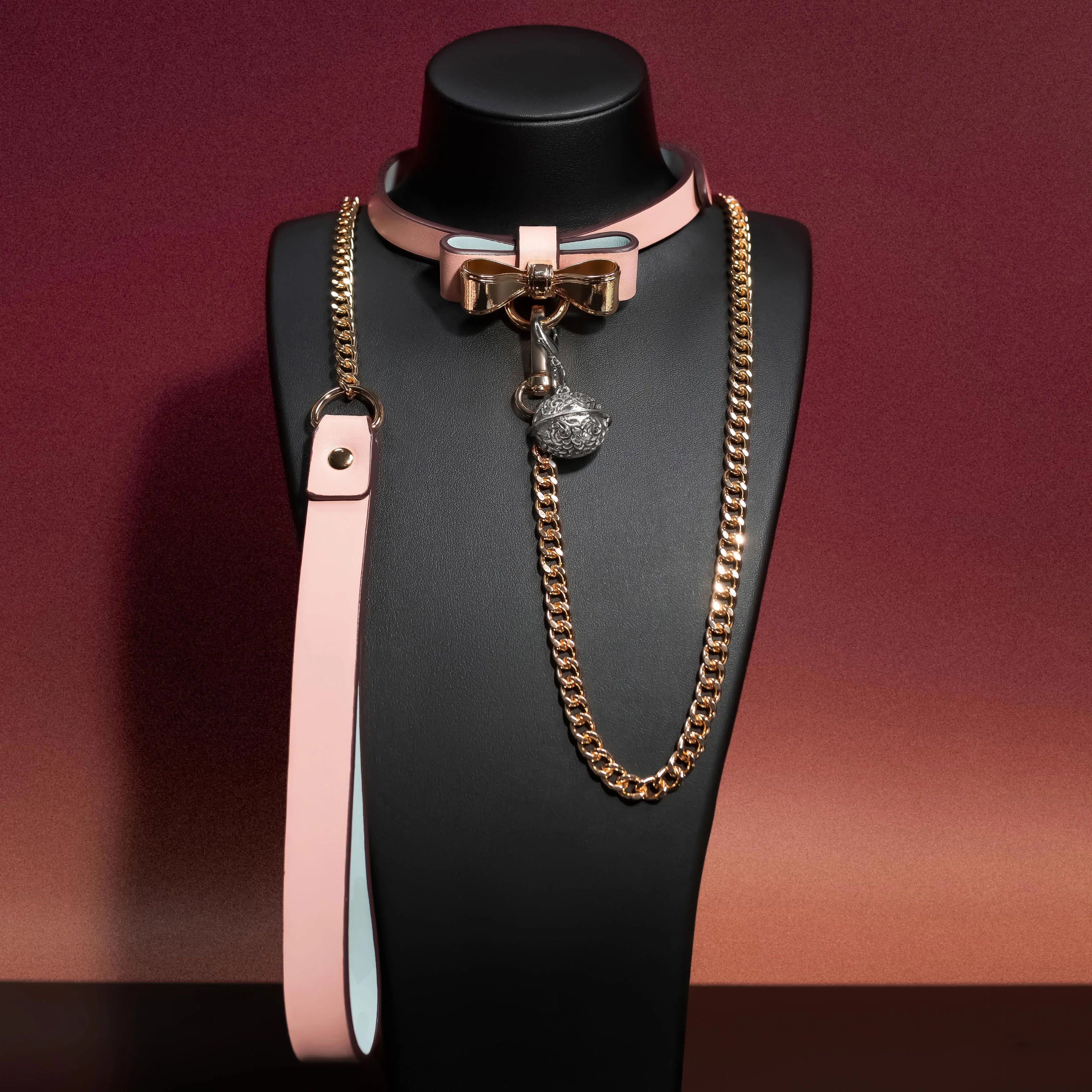 Pink bow collar with gold chain displayed front angle on black mannequin