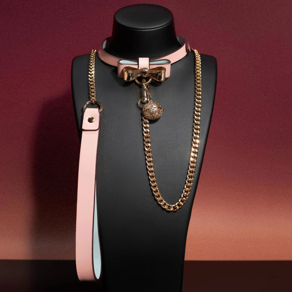 Pink pet collar with gold bow hardware and chain leash, front display on mannequin